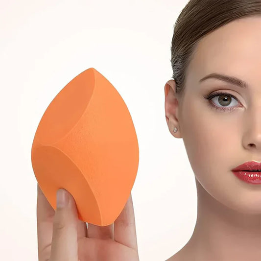 Kvinne holder en oransje sminkesvamp for påføring av foundation og makeup.